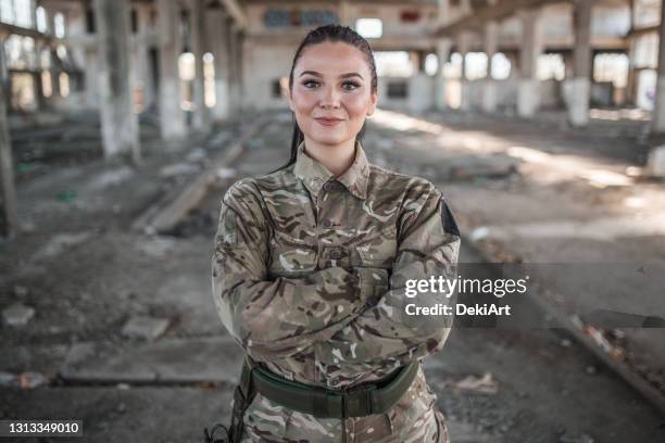 mooie vrouwelijke militair met gekruiste wapens in eenvormig - army soldier stockfoto's en -beelden