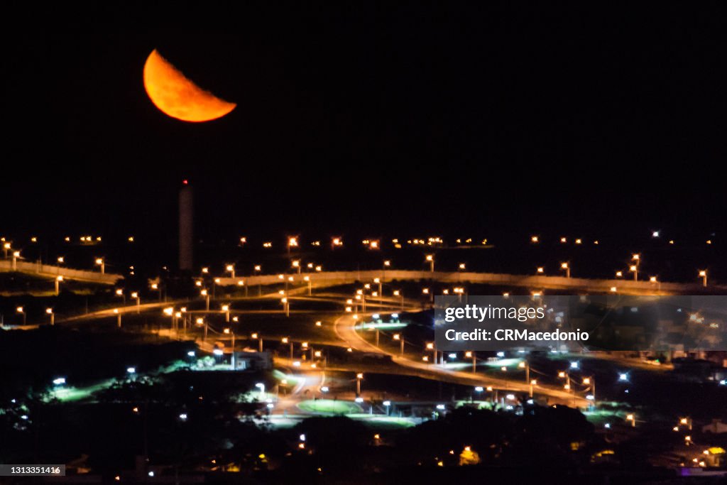 The huge moon with all its splendor on deserted streets and orange color lighting.