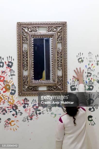 a young girl making multicolor hand print paintings on wall around a silver mirror. - 9 hand drawn patterns stock-fotos und bilder