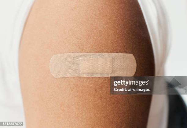 adhesive bandage, on the arm of a black man after giving him the covid19 vaccine. - band aid fotografías e imágenes de stock