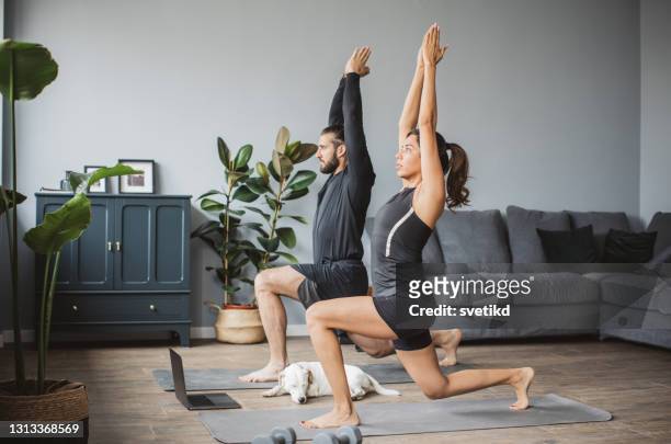 couple practicing yoga at home - yoga stock pictures, royalty-free photos & images