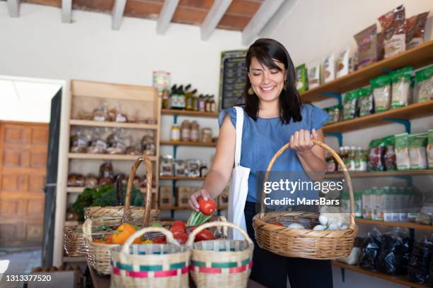 young woman smiling buying vegetables and food at small local store - small store stock pictures, royalty-free photos & images