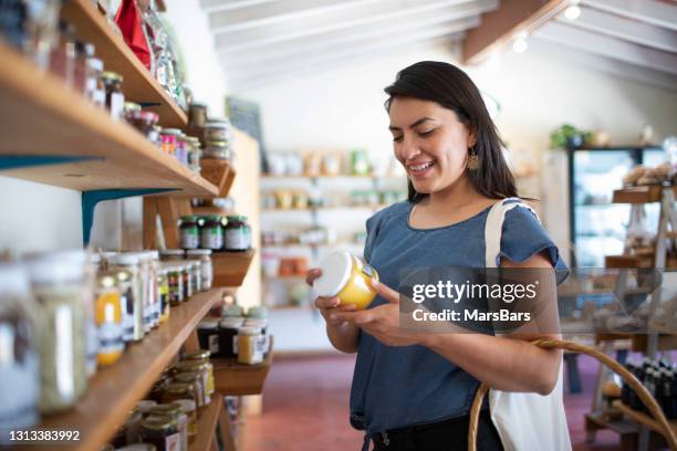 年輕女子微笑著在當地小商店購買健康手工食品 - 商品 個照片及圖片檔