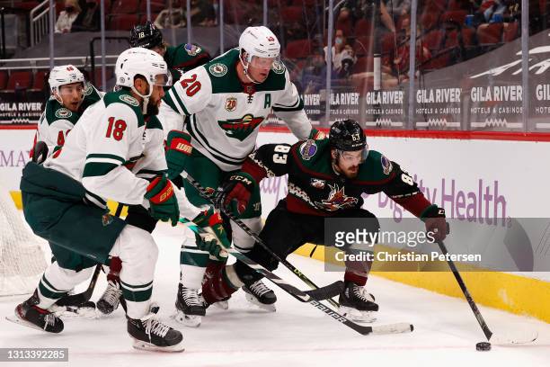 Conor Garland of the Arizona Coyotes attempts to control the puck pressured by Ryan Suter and Jordan Greenway of the Minnesota Wild during the second...
