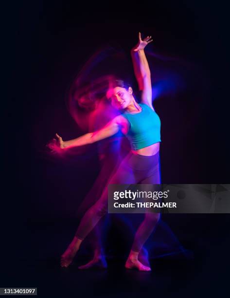 ragazza che fa mosse di danza contemporanea con effetti di luce al rallentatore viola - contemporary dance foto e immagini stock