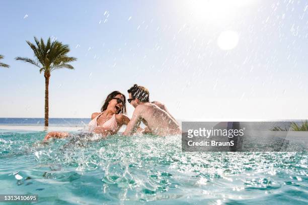 cheerful couple having fun in the infinity pool. - infinity pool stock pictures, royalty-free photos & images