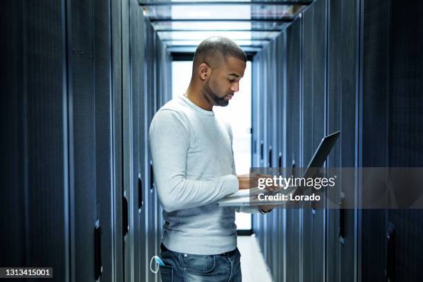 een zwarte mannelijke technicus die van de serverruimte bij bedrijfs het heropenen werkt - beveiliging stockfoto's en -beelden