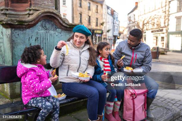 eating chips in the town centre - family eating potato chips imagens e fotografias de stock