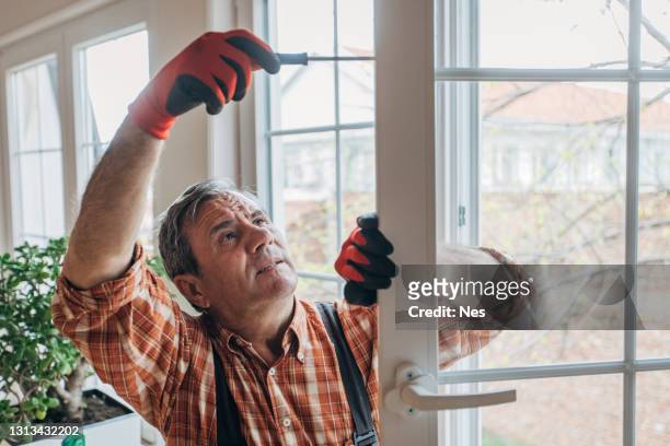 un trabajador instala ventanas - window fotografías e imágenes de stock