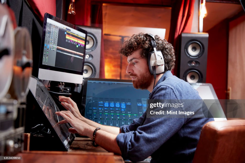 Man working in music studio using computer wearing head phones