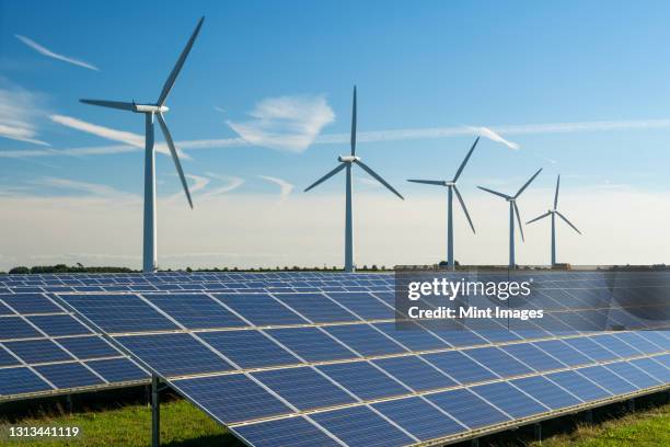 wind turbine energy generaters on wind farm, with solar panels underneath. - windenergie stockfoto's en -beelden