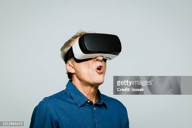 homme aîné utilisant des glaces virtuelles de réalité - lunettes de pilote de course photos et images de collection