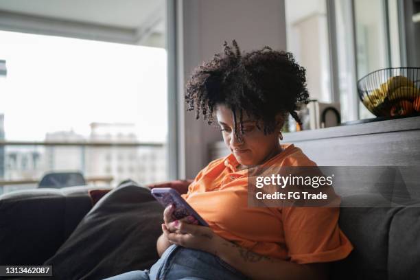 joven usando teléfono inteligente en casa - mala postura fotografías e imágenes de stock