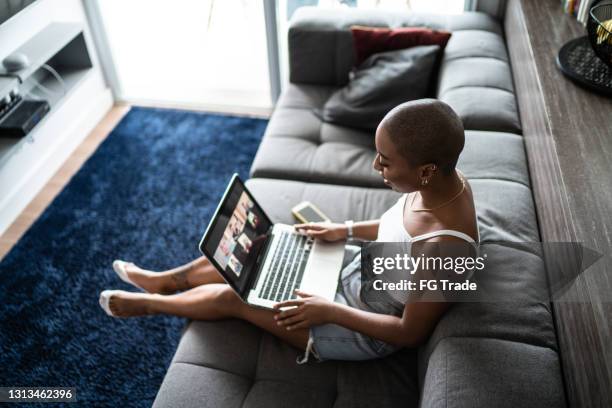 jeune femme faisant un appel vidéo sur l’ordinateur portatif à la maison - relation à distance photos et images de collection