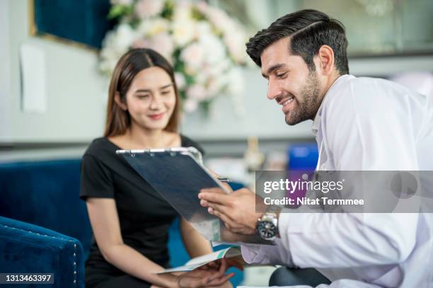 doctor wearing a uniform consultation and explaining to a young woman patient about a botox injection detail in the beauty clinic. skin care clinic business. - chirurgo plastico foto e immagini stock