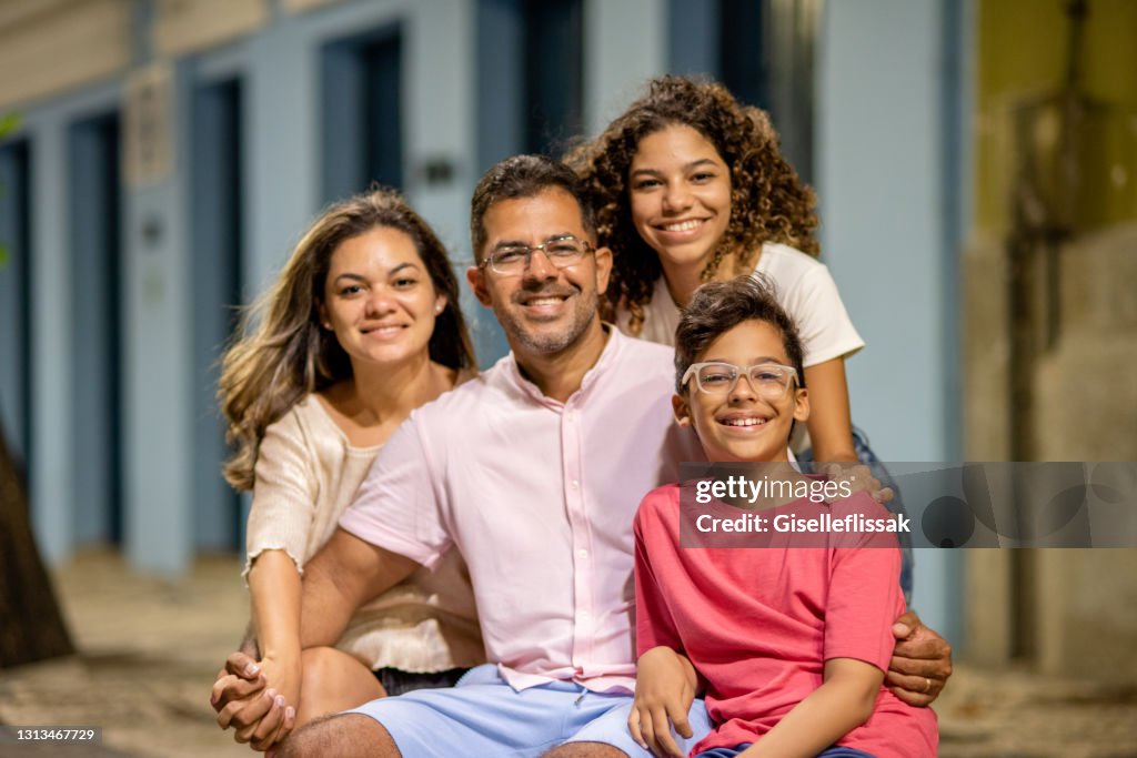 Família sorridente sentadas juntas em um banco da cidade à noite
