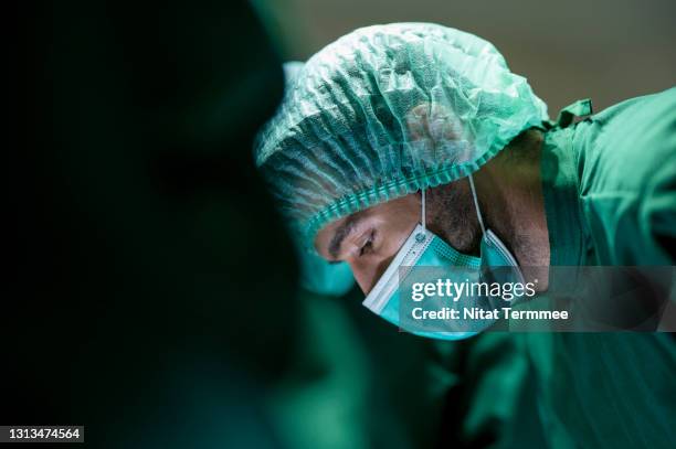 side view of plastic surgeon operating patient for breast implant at operating room. they are in surgical gown. plastic surgery and beauty business. - nurse thinking stock pictures, royalty-free photos & images