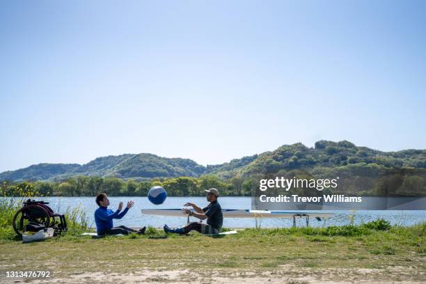 paraplegic athlete and his coach doing warming up exercises beside a river before training - okayama prefecture stock pictures, royalty-free photos & images