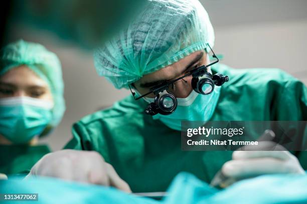 the business of plastic surgery. surgeons operating patient for breast implant in surgery clinic. - surgeon patient stock pictures, royalty-free photos & images