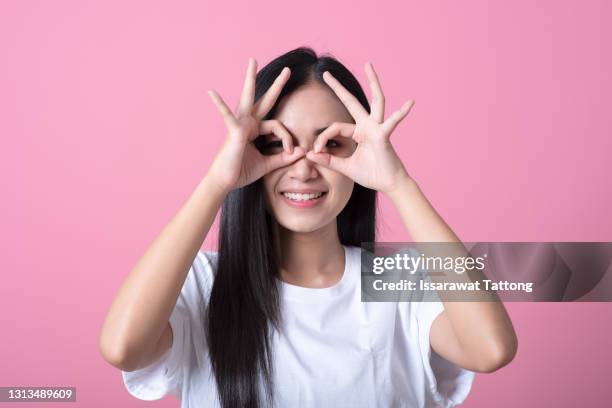 cheerful excited female with blonde long straight hair showing ok gestures with both hands, pretending to wear spectacles, and smiling broadly, enjoying her carefree happy life - okサイン　女性 ストックフォトと画像