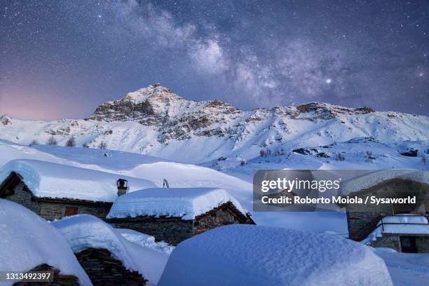 snowy mountain huts under milky way, valtellina, italy - steinhaus stock-fotos und bilder