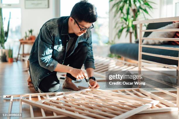 young father assembling baby cot at home - furniture maker foto e immagini stock