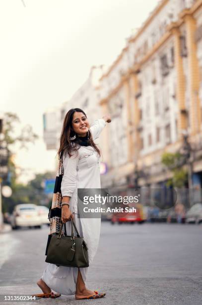 young woman waiting for taxi or bus on road - bangalore tourist stock pictures, royalty-free photos & images