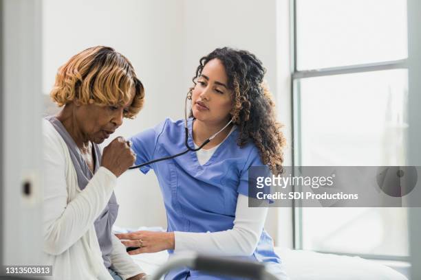 nurse uses stethoscope to listen to senior's lungs - old cough stock pictures, royalty-free photos & images