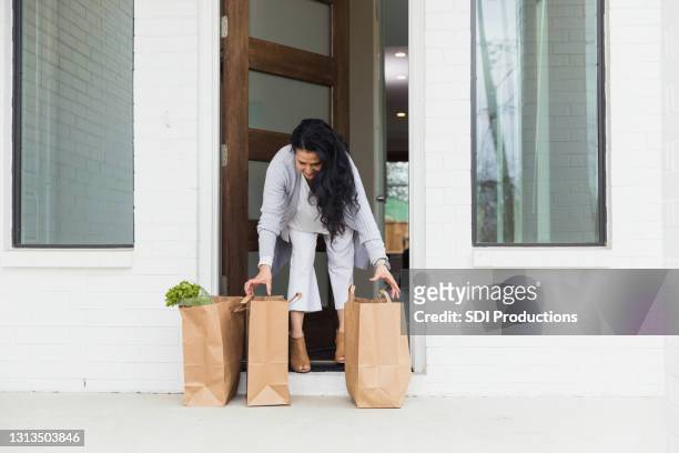 mature woman steps out to pick up e-commerce grocery order - bent stock pictures, royalty-free photos & images