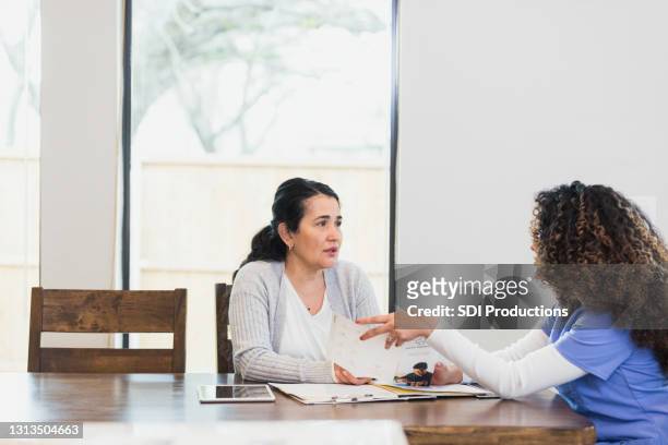 mature woman discusses healthcare with nurse - blank pamphlet stock pictures, royalty-free photos & images
