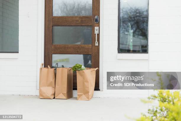 drei papiertüten von lieferer an haustür zurückgelassen - zuhause-bleiben-anordnung stock-fotos und bilder