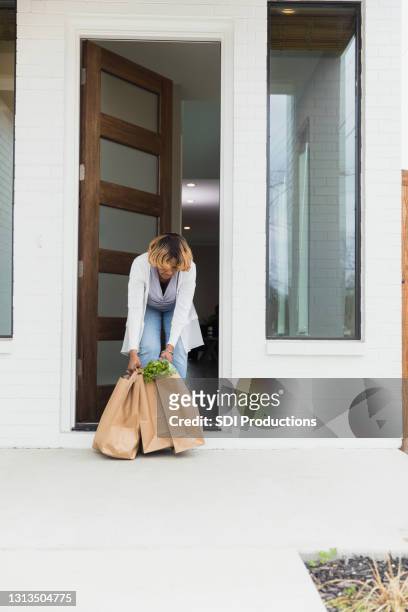 unrecognizable senior woman brings in heavy bags full of food - social distancing shopping stock pictures, royalty-free photos & images