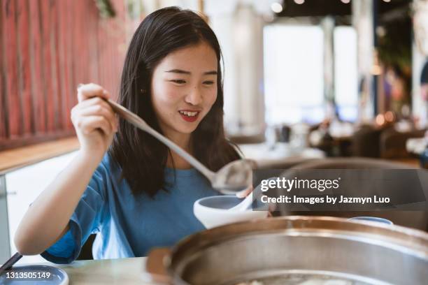 a chinese girl is eating hot pot in a restaurant - hot pots stock pictures, royalty-free photos & images