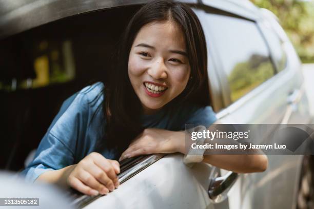 weekend trip, a chinese girl smiling and enjoying the scenery outside the car window - toyota care toyota stock pictures, royalty-free photos & images