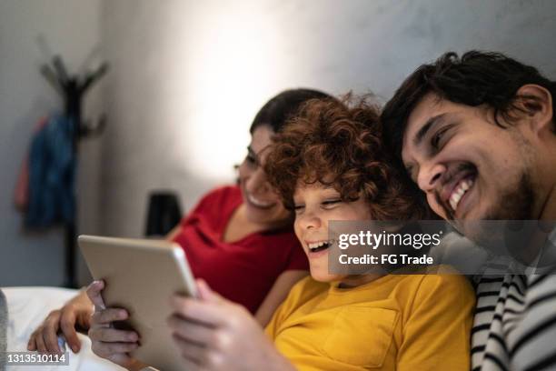 family using digital tablet in bed at home - family game night stock pictures, royalty-free photos & images