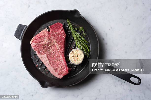raw t-bone steak on cast iron pan - schwein grill stock-fotos und bilder