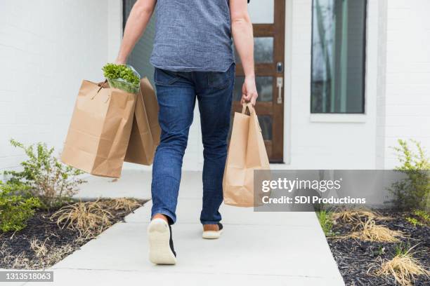 man briskly delivers three bags of groceries to home - carrier stock pictures, royalty-free photos & images