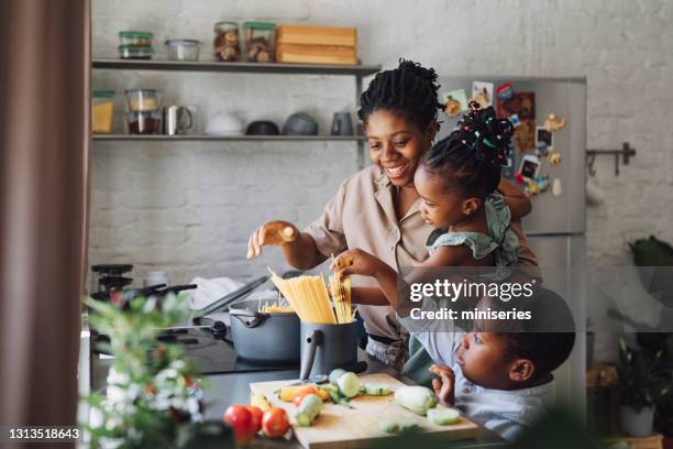 mère, descendant et fils préparant des spaghettis et des légumes pour le déjeuner - black mom photos et images de collection