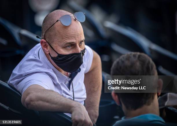 New York Yankees general manager Brian Cashman talks to someone while wearing a face mask during spring training at George Steinbrenner Field in...