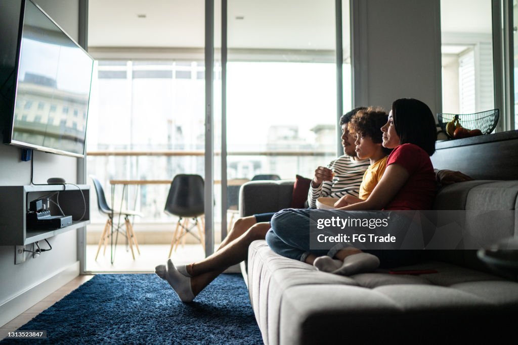 Family watching tv and eating popcorn at home
