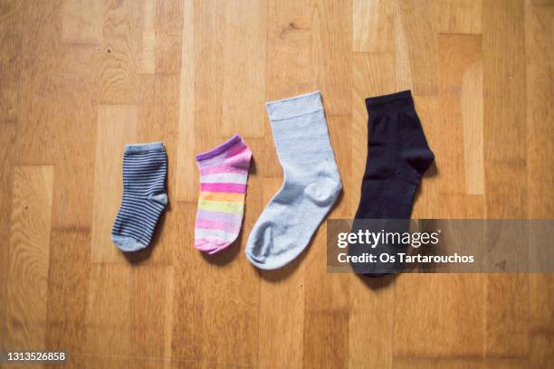 four unpaired socks representing family lying on the floor - depictions stockfoto's en -beelden