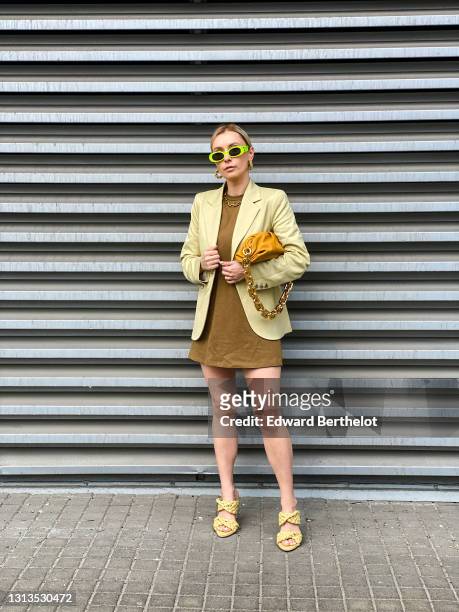 Justyna Czerniak wears neon green / yellow sunglasses from Gucci, a golden necklace, a beige oversized blazer jacket from Baum und Pferdgarten, a...