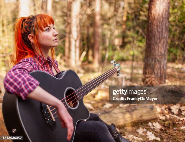 verträumte junge frau spielt gitarre im waldgarten im freien in einer umgebung von bäumen und frühling oder sommer - sänger und komponist stock-fotos und bilder