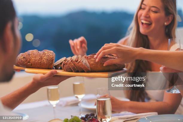 group of friends sharing a loaf of bread at a dinner party. - man offering bread stock pictures, royalty-free photos & images