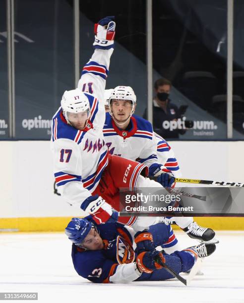 Ryan Lindgren and Kevin Rooney of the New York Rangers trip up Mathew Barzal of the New York Islanders during the first period at the Nassau Coliseum...