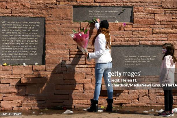 Brandy Muñoz and her daughter Jazzy right, leave flowers under placards with quotes at the Columbine Memorial at Robert F. Clement Park on April 20,...