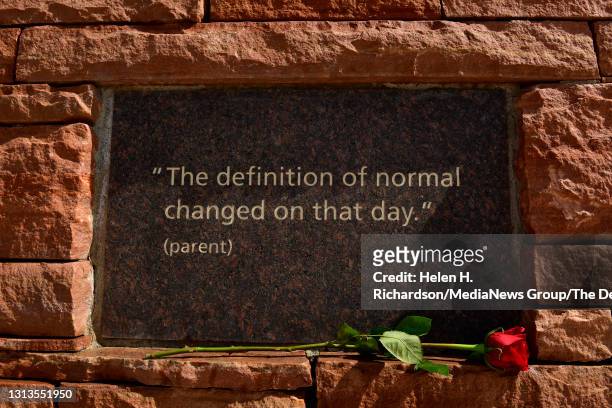 Rose is left beneath a placard along a stone wall that has quotes from those affected by the shooting at the Columbine Memorial at Robert F. Clement...