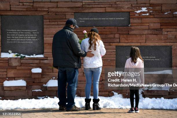 Anthony Muñoz, left, his wife Brandy and daughter Jazzy right, leave flowers under placards with quotes at the Columbine Memorial at Robert F....