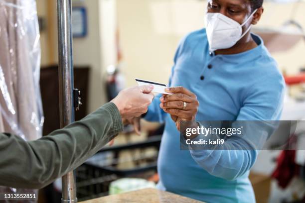 worker at dry cleaners taking payment from customer - handing over credit card stock pictures, royalty-free photos & images