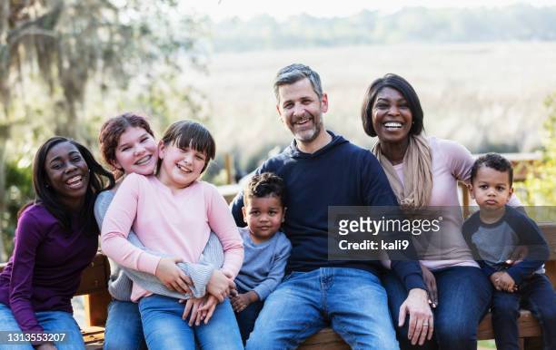 gemengd gezin met vijf kinderen die op parkbank zitten - blended family stockfoto's en -beelden